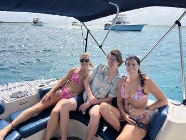 A cheerful group relaxes on a boat, enjoying the sunny weather and beautiful turquoise waters — perfect for a day of fun on the water.