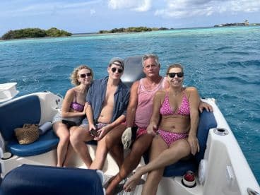 A cheerful group enjoys a day on the water, relaxing on a boat with stunning turquoise waters in the background — perfect for a fun-filled beach outing.