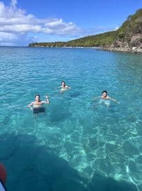 Three friends enjoy a refreshing swim in crystal-clear waters, surrounded by beautiful scenery — a perfect day for fun and relaxation.