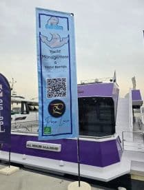 A promotional banner for yacht management and rentals displayed next to a purple yacht, featuring contact information and a QR code for easy access.