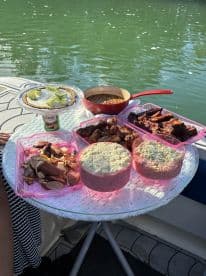 A delicious spread of BBQ and sides is laid out on a table aboard a boat, perfect for enjoying a meal while cruising on the water.