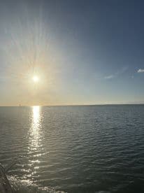 A serene view of the sun setting over calm waters, creating a beautiful reflection — perfect for capturing tranquil moments on the water.
