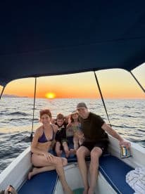A joyful family enjoys a sunset cruise on their boat, capturing a perfect moment of togetherness and celebration on the water.