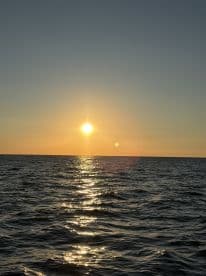 A stunning sunset over the ocean, reflecting shimmering light on the water's surface — a perfect backdrop for evening boat trips and romantic cruises.