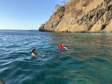 Two individuals enjoy a refreshing swim in the clear ocean waters, showcasing a perfect day of adventure and exploration in a beautiful coastal setting.