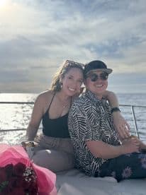 A happy couple enjoys drinks together on a boat, capturing a perfect moment of celebration against a stunning ocean backdrop.