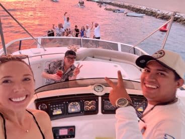 A joyful group of friends enjoys a sunset cruise on a boat, capturing fun moments and celebrations against a vibrant backdrop.
