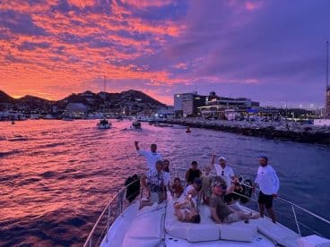 A lively group enjoys a stunning sunset cruise in Cabo San Lucas, capturing the essence of celebration on the water with friends and family.