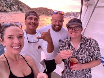 A cheerful group enjoys drinks and smiles aboard a boat during a stunning sunset, capturing the essence of celebration on the water.