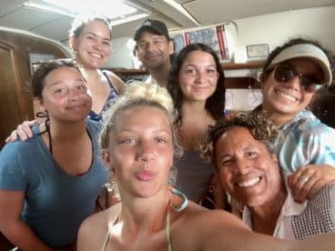 A cheerful group of friends poses for a selfie inside a boat, capturing the joyful spirit of their adventure together.