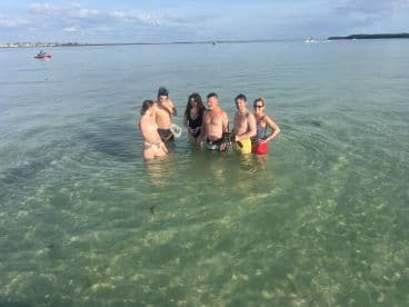 A lively group enjoys a fun day in the shallow waters, perfect for swimming and beach activities — an ideal setting for memorable outings.