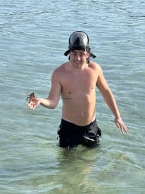 A snorkeler holds a lobster while wading in clear waters, showcasing an exciting underwater adventure and the thrill of marine life exploration.