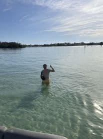 A man enjoys a refreshing swim in crystal-clear waters, giving a thumbs up to capture the fun of a perfect day on the water.