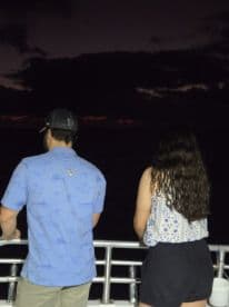A couple enjoys a serene moment together on a boat, gazing at the sunset over the horizon — perfect for romantic evenings on the water.