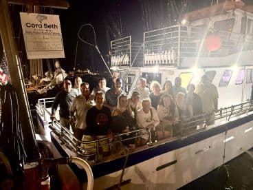 A lively group gathers on the deck of a fishing boat at night, ready for an exciting fishing adventure — perfect for creating unforgettable memories on the water.