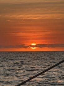 A stunning sunset over the ocean, viewed from a boat, creating a picturesque backdrop for evening cruises.