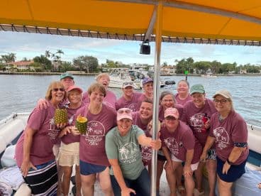 A joyful group celebrates a 50th birthday aboard a pontoon boat, showcasing fun and camaraderie on the water.