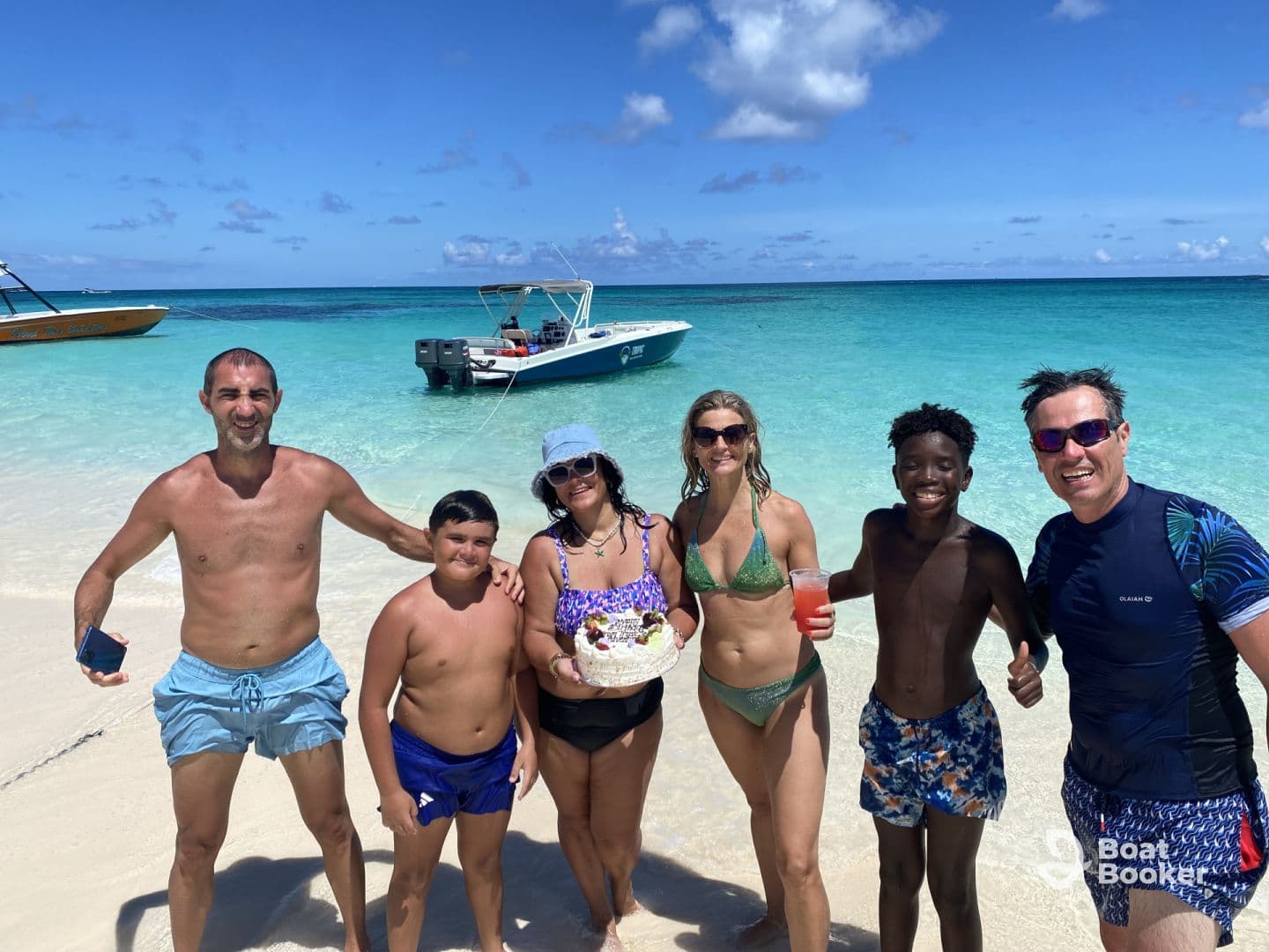 A joyful group of friends and family enjoys a beach day, celebrating with drinks and food in the beautiful turquoise waters — a perfect getaway moment.
