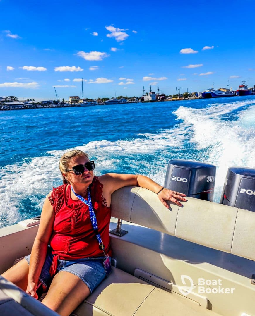 A woman relaxes on the deck of a boat, enjoying the vibrant blue waters and sunny skies — a perfect moment for a day out on the water.