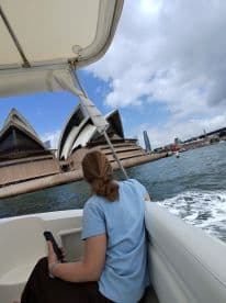 A woman enjoys a scenic boat ride past the iconic Sydney Opera House, capturing the essence of a memorable day on the water.
