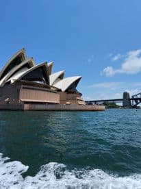 A stunning view of the Sydney Opera House with the Harbour Bridge in the background, showcasing iconic Australian landmarks from the water.