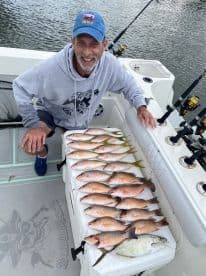 A proud angler displays a successful catch of fish aboard a boat, showcasing the thrill of fishing adventures on the water.
