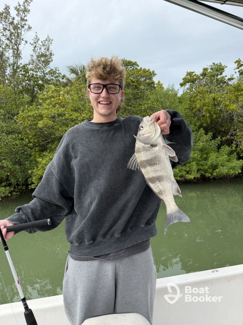 A young man proudly displays his catch while fishing from a boat, showcasing the excitement of a successful day on the water.