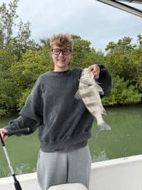 A young man proudly displays his catch while fishing from a boat, showcasing the excitement of a successful day on the water.