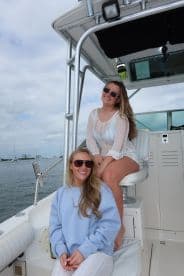 Two friends enjoy a sunny day on the boat, showcasing the perfect atmosphere for a fun outing on the water.