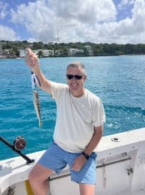 A man proudly displays his catch while fishing from a boat, showcasing the excitement of a day on the water.