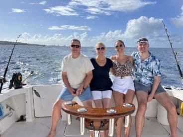 A cheerful group of friends enjoys a fishing trip on a boat, capturing the essence of fun and adventure on the open ocean.