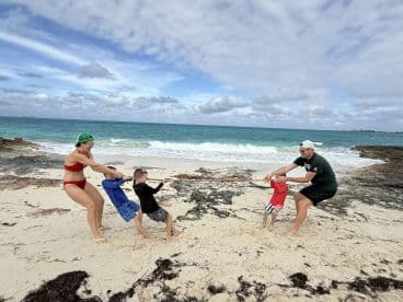 A fun family tug-of-war game on the beach, showcasing laughter and bonding moments against a beautiful ocean backdrop.