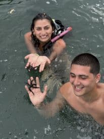 Two snorkelers joyfully interact with starfish in the water, showcasing a memorable wildlife experience during their aquatic adventure.