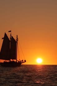 A majestic sailing ship silhouetted against a stunning sunset, creating a picturesque scene perfect for group celebrations and evening cruises.