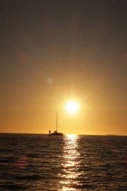 A serene sunset view of a sailboat silhouetted against the golden horizon, creating a picturesque scene perfect for romantic evenings on the water.