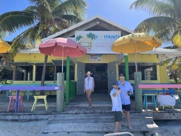 A lively group enjoys a sunny day at Footprints Beach Bar, capturing memories with a selfie in front of the vibrant establishment.