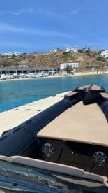 A sleek speedboat is docked with a stunning view of turquoise waters and a beachside resort in the background, perfect for summer adventures.