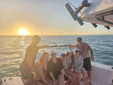 A joyful group of friends poses on a boat at sunset, capturing a memorable moment of celebration on the water.