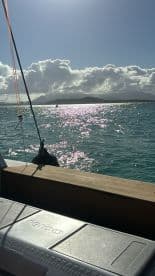 A serene view of the ocean with sparkling sunlight reflecting on the water, showcasing the beauty of the surrounding islands — perfect for a tranquil boating experience.