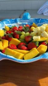 A vibrant fruit platter featuring strawberries, mango, pineapple, and grapes, perfect for refreshing snacks on a boat trip.