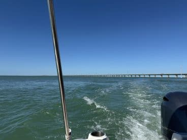 A scenic view from a boat cruising through calm waters, showcasing a distant bridge against a clear blue sky — perfect for adventure seekers and boating enthusiasts.