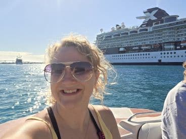 A cheerful selfie taken on the water with a cruise ship in the background, capturing the joy of a boating adventure.