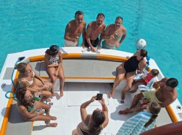 A lively group enjoys drinks and fun on a boat in crystal-clear waters, perfect for a day of celebration and relaxation.
