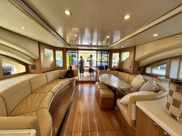 A spacious and elegantly designed interior of a boat featuring comfortable seating and a dining area, perfect for relaxing and enjoying the views while on the water.