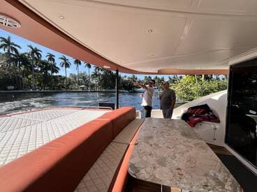 Two men enjoy the spacious interior of a boat, discussing the view while surrounded by comfortable seating and a scenic waterfront backdrop.