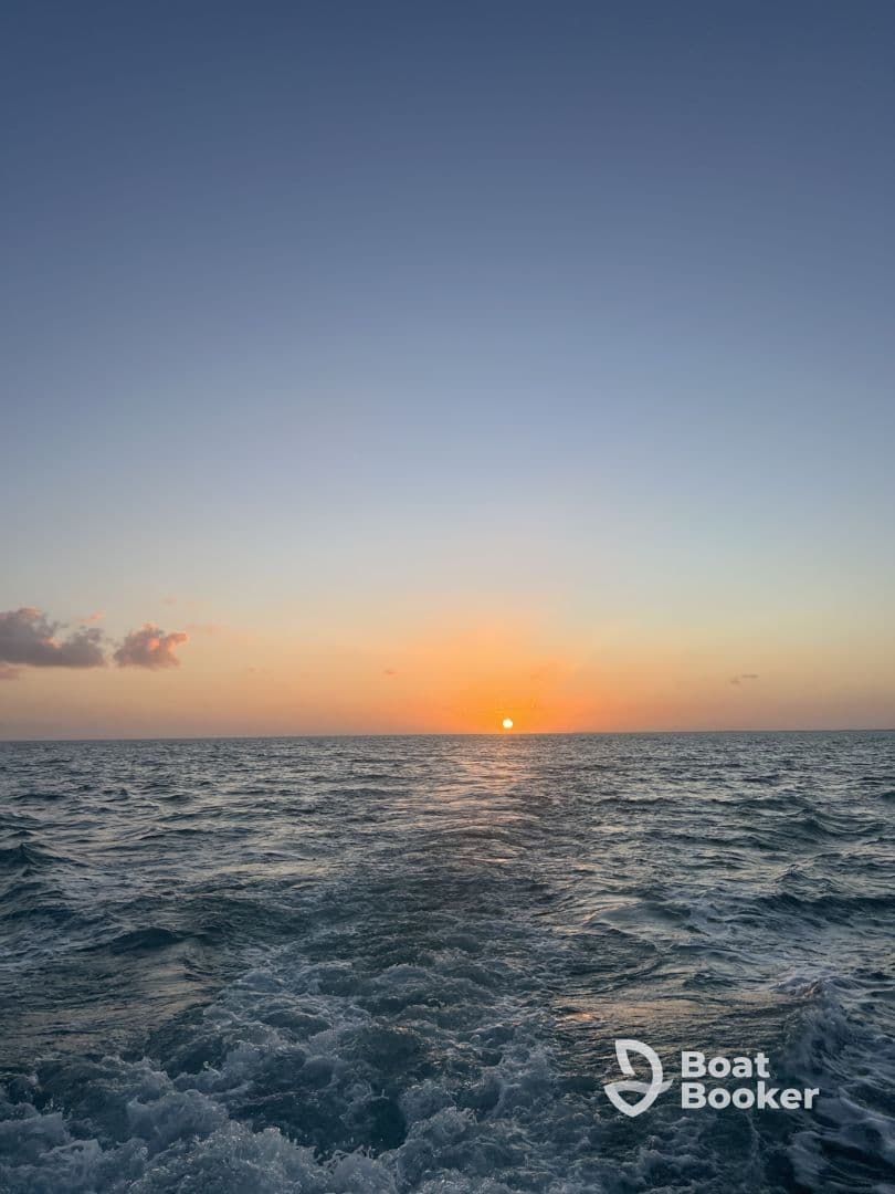 A serene sunset over the ocean, captured from the back of a boat, showcasing the tranquil beauty of a day ending at sea.
