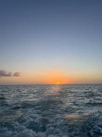A serene sunset over the ocean, captured from the back of a boat, showcasing the tranquil beauty of a day ending at sea.