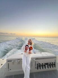 A joyful moment on a boat at sunset, featuring a woman holding playful cutouts of a dog and a person, perfect for capturing fun memories on the water.