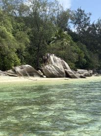 A serene view of a tropical beach featuring large rocks and clear turquoise waters, perfect for showcasing the natural beauty of coastal destinations.