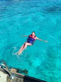 A joyful swimmer enjoys the clear turquoise waters, showcasing a fun and safe experience with a life jacket — perfect for water adventures.